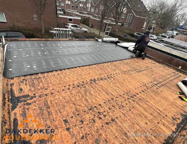 Dakdekker legt onderlaag op plat dak met houten constructie in Woudenberg