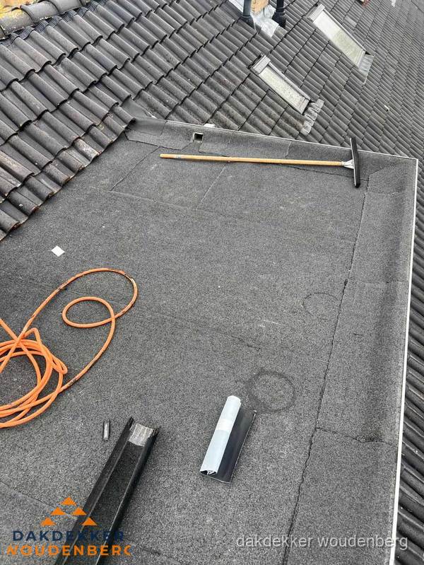 Plat dak reparatie met gereedschap en loodstroken in Woudenberg