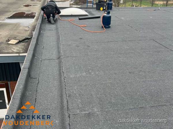 Dakdekker repareert bitumen dakbedekking op groot plat dak in Woudenberg Dakdekker repareert bitumen dakbedekking op groot plat dak in Woudenberg