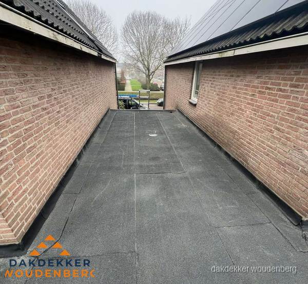 Plat dak met bitumen dakbedekking tussen bakstenen muren in Woudenberg Plat dak met bitumen dakbedekking tussen bakstenen muren in Woudenberg