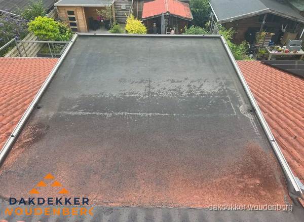 Verouderd plat dak met slijtage tussen schuine daken in Woudenberg Verouderd plat dak met slijtage tussen schuine daken in Woudenberg